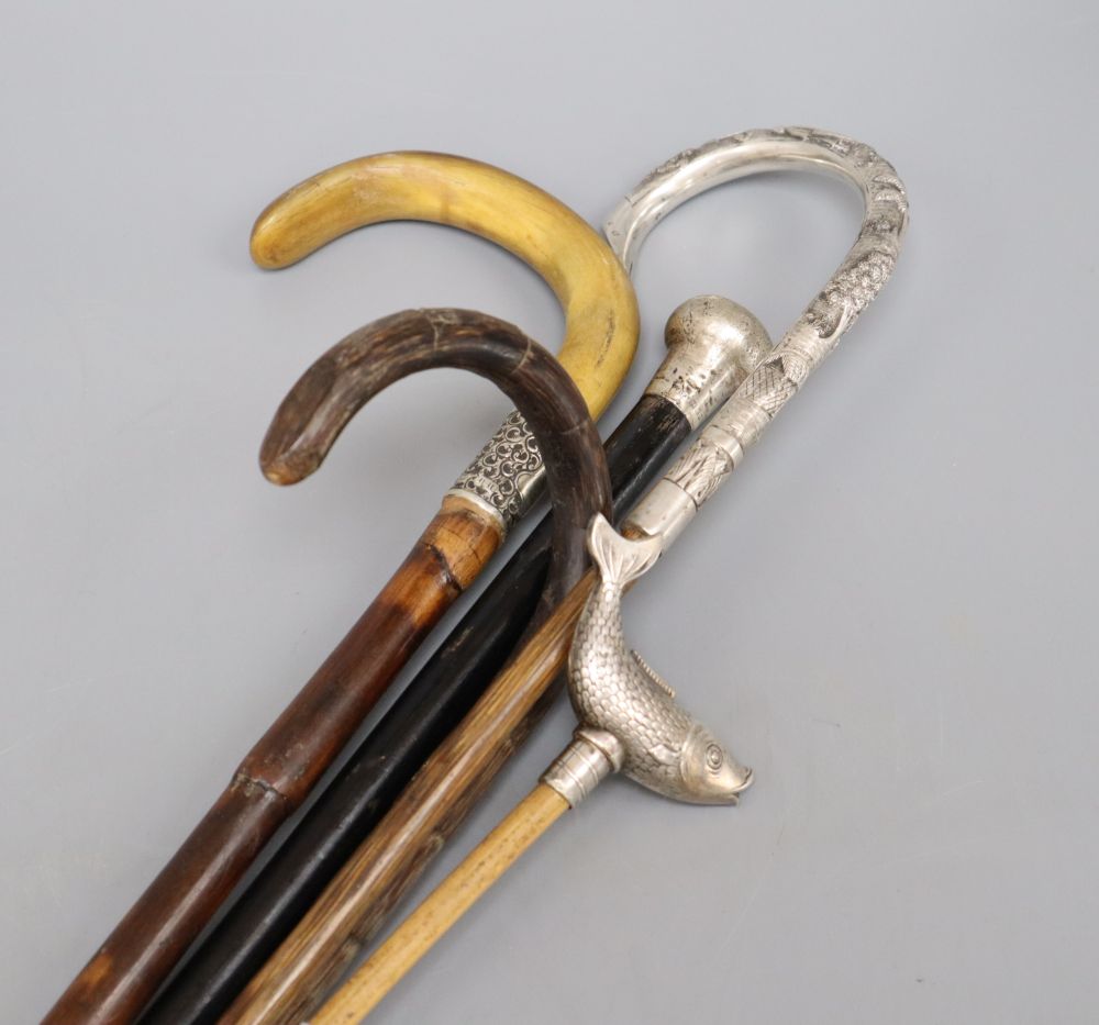 Four various walking canes and a fish pointer